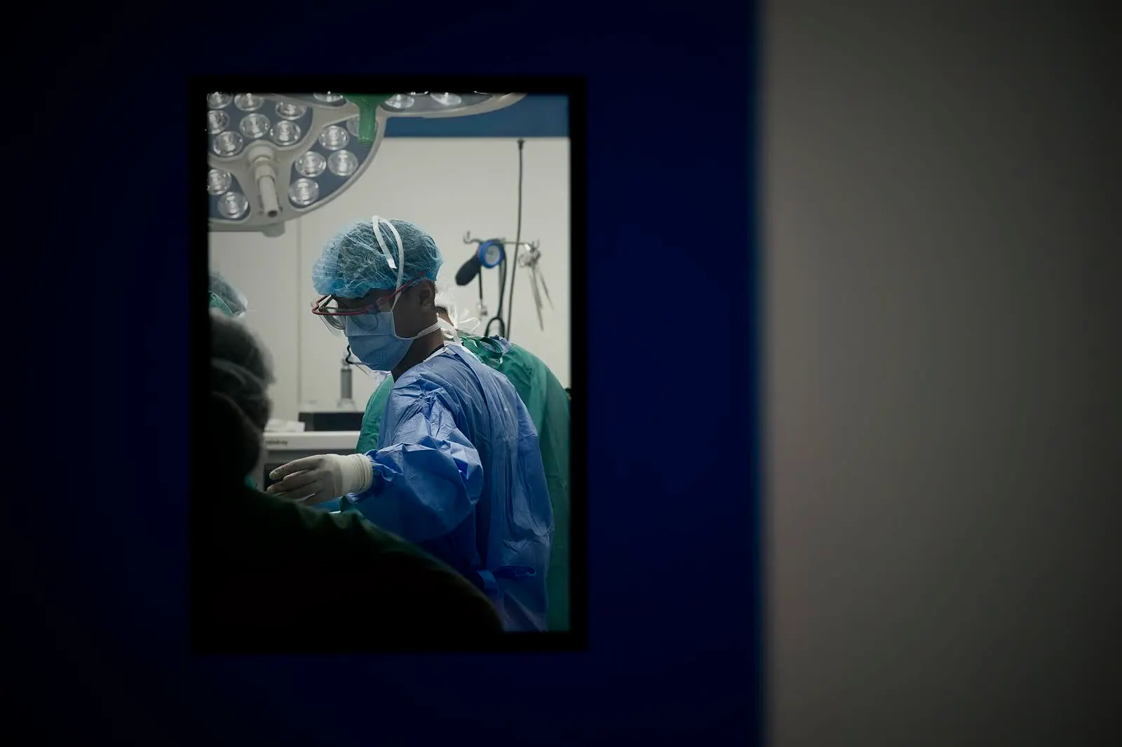 Surgeons seen through the window of an operating room door